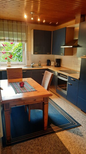 Eine moderne Küche mit dunkelblauen Schränken, einem Holzes Esstisch und einem eingebauten Backofen.