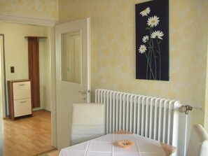 Ein Schlafzimmer mit Heizkörper, Nachttisch und einem Wandbild mit Gänseblümchen.