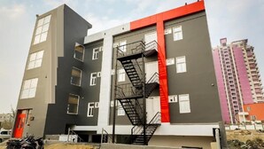 A multi-story building with a prominent red and grey facade, a central staircase, and a red door. - Hotel Golden World  (Ghaziabad)