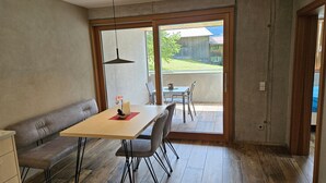 A dining area with a wooden table, chairs, a bench, and a hanging light fixture.