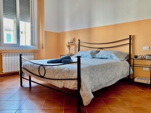 Une chambre à coucher avec un lit, un radiateur, une fenêtre et une table de chevet.