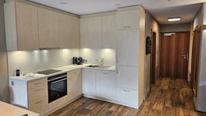 Una cocina moderna con armarios de madera clara, horno empotrado y pileta de acero inoxidable.