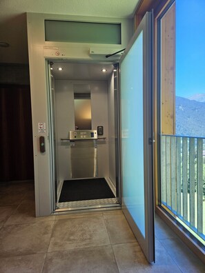 An elevator with a digital display, a control panel, and a small shelf.