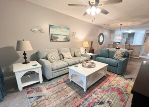 Ein Wohnzimmer mit zwei Sofas, einem Couchtisch, einer Lampe und einem Gemälde an der Wand.