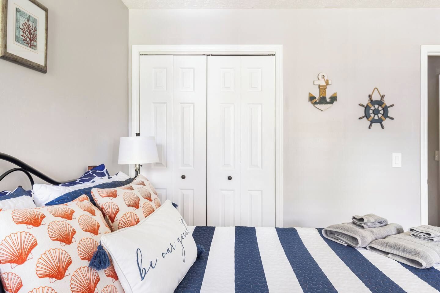 Une chambre à coucher comprenant un lit, des oreillers, une lampe, une armoire et deux éléments de décoration murale.