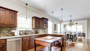 A modern kitchen with wooden cabinets, a stone backsplash, and a central island. - Lovely Home & Guest Suite. Walk to City & Stadium. (Charlotte)