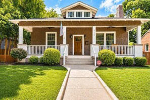 A two-story house with a front porch, a mailbox, and a stop sign.