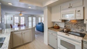 A modern kitchen with white cabinets, a granite countertop, and a built-in oven. - South Mission Beach Gem, Steps to Bay, Dual Patios (San Diego)