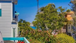 A modern building with a balcony, surrounded by lush greenery and a clear blue sky. - South Mission Beach Gem, Steps to Bay, Dual Patios (San Diego)