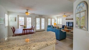 A spacious living area with a large kitchen island, a dining table, and a blue sofa. - South Mission Beach Gem, Steps to Bay, Dual Patios (San Diego)