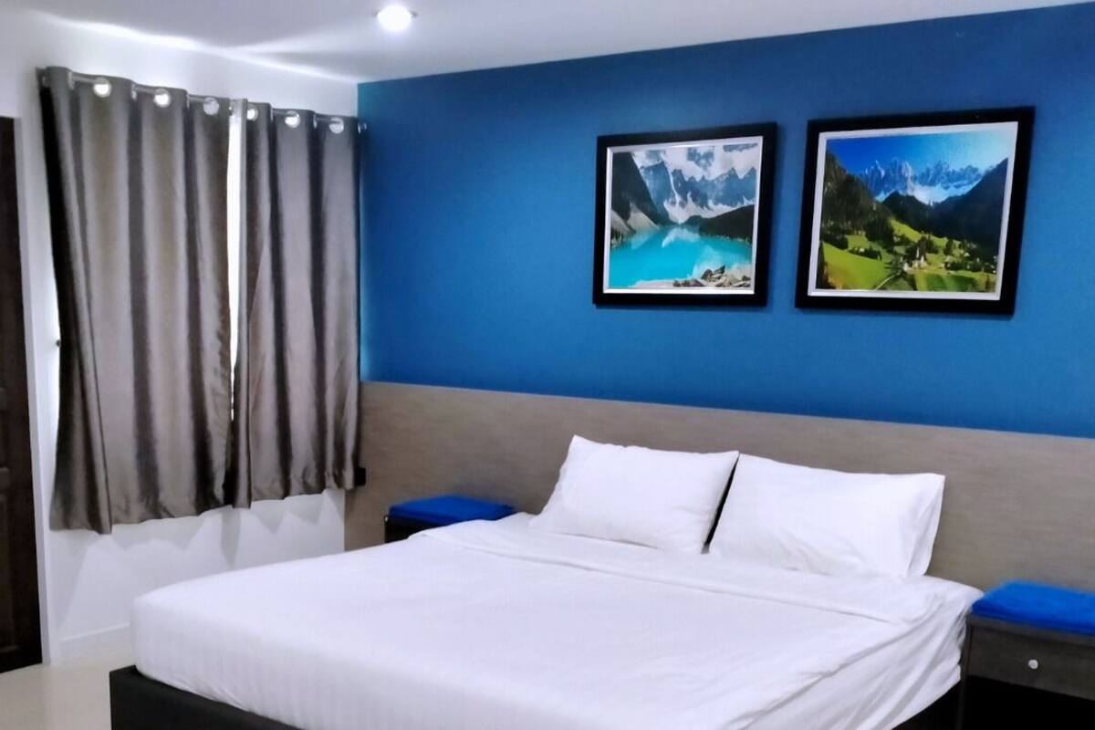 A modern bedroom with a large bed, two framed pictures on the wall, and a decorative wall hanging.