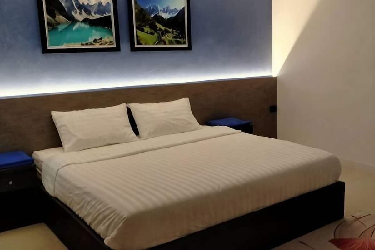 A neatly made bed with a headboard, two bedside tables, and framed pictures on the wall.