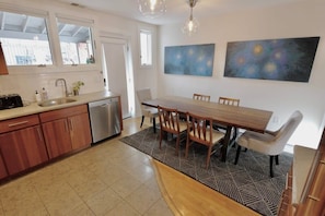 A modern kitchen with a dining area, wooden cabinets, a stainless steel sink, and a dining table with chairs.