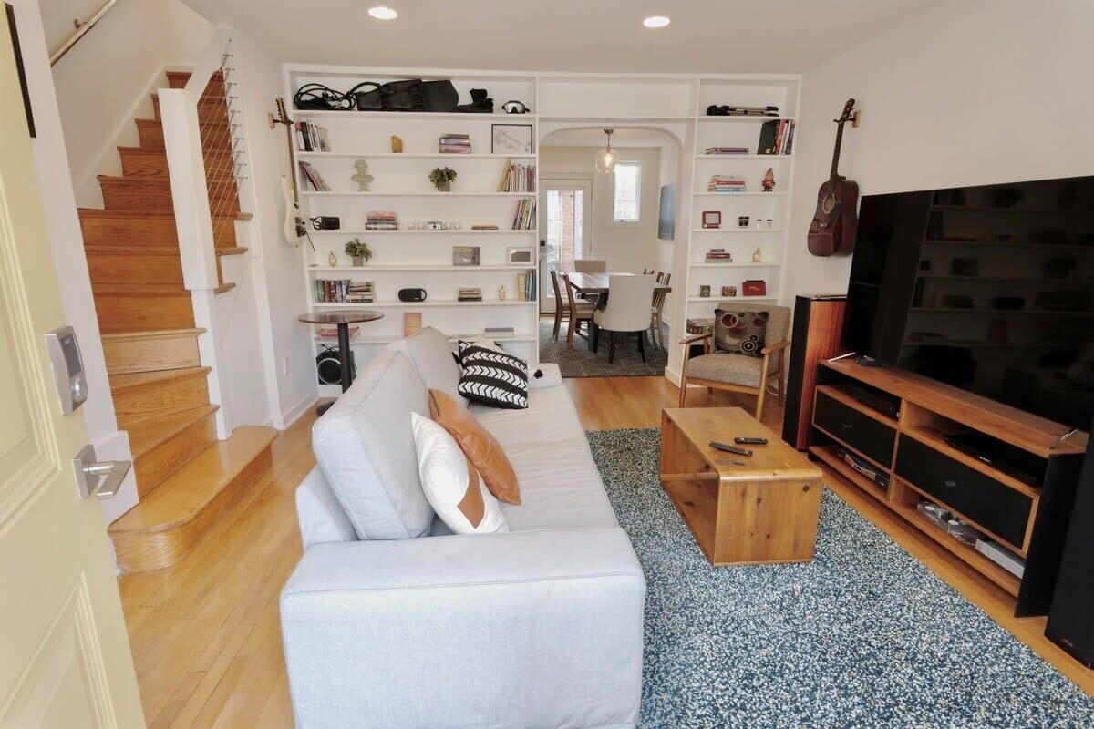 A modern living room with a sofa, coffee table, TV, and built-in shelves.