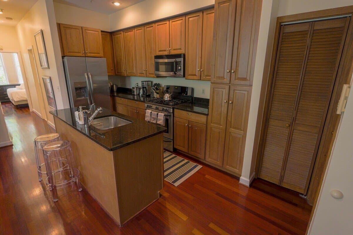 A modern kitchen with wooden cabinets, a stainless steel refrigerator, a microwave, and a gas stove.