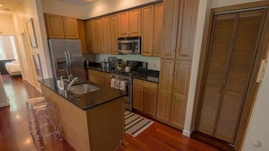 A modern kitchen with wooden cabinets, a stainless steel refrigerator, a microwave, and a gas stove.