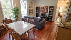 A spacious living area with a dining table, sofas, and a TV.