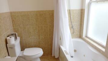 A bathroom with a toilet, bidet, bathtub, and a window.