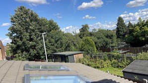 Ein Dach mit Oberlichtern, ein kleines Gartenhaus und ein hoher Baum.