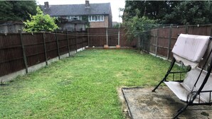 Ein Garten mit Rasenfläche, Holzzaun und Schaukel.