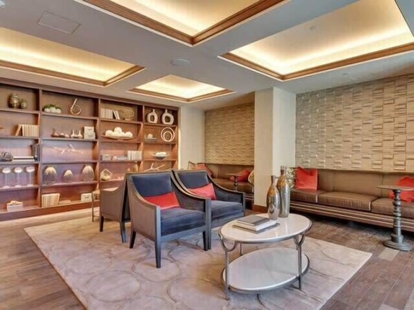 Un salon moderne comprenant un canapé, des fauteuils, une table basse et une bibliothèque remplie d’objets décoratifs.