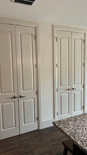 A room with two white doors, a wooden floor, and a granite countertop. - Preston Royal Single I Premium 1BR in Dallas (Dallas)