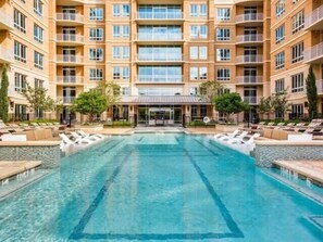 Un hôtel à plusieurs étages doté d’une piscine centrale, d’un espace extérieur aménagé et d’une entrée couverte.