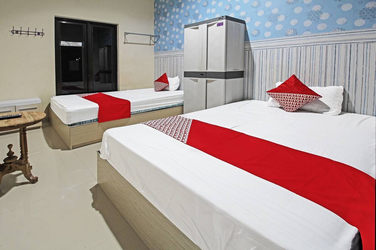 Una habitación de hotel con dos camas, un armario, una mesita y un espejo.