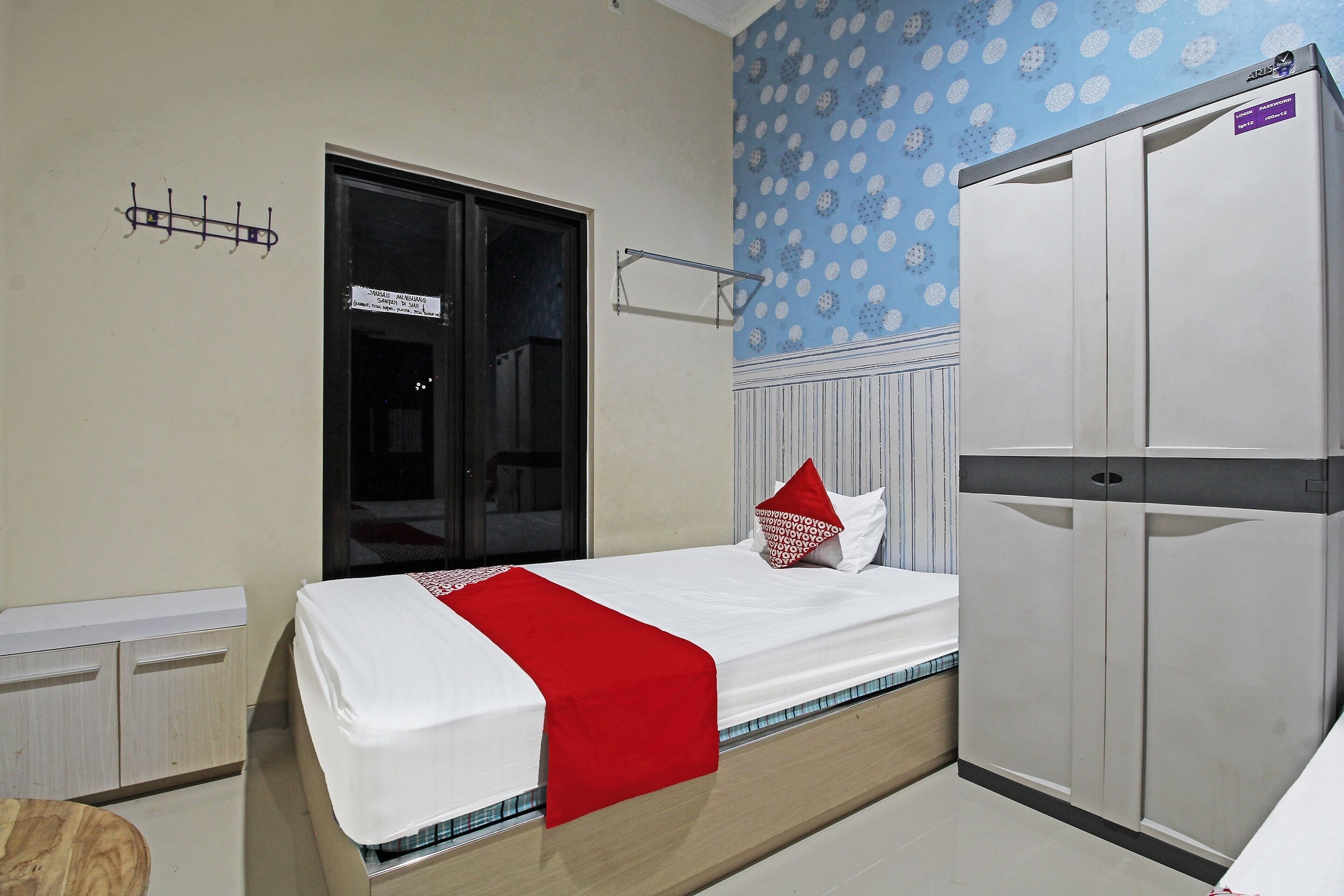 Un dormitorio con una cama, un armario, una ventana y una pared con estampado de lunares.