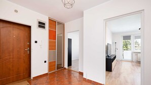 A hallway with a wooden door, a sliding glass door, a tiled floor, and a black cabinet.