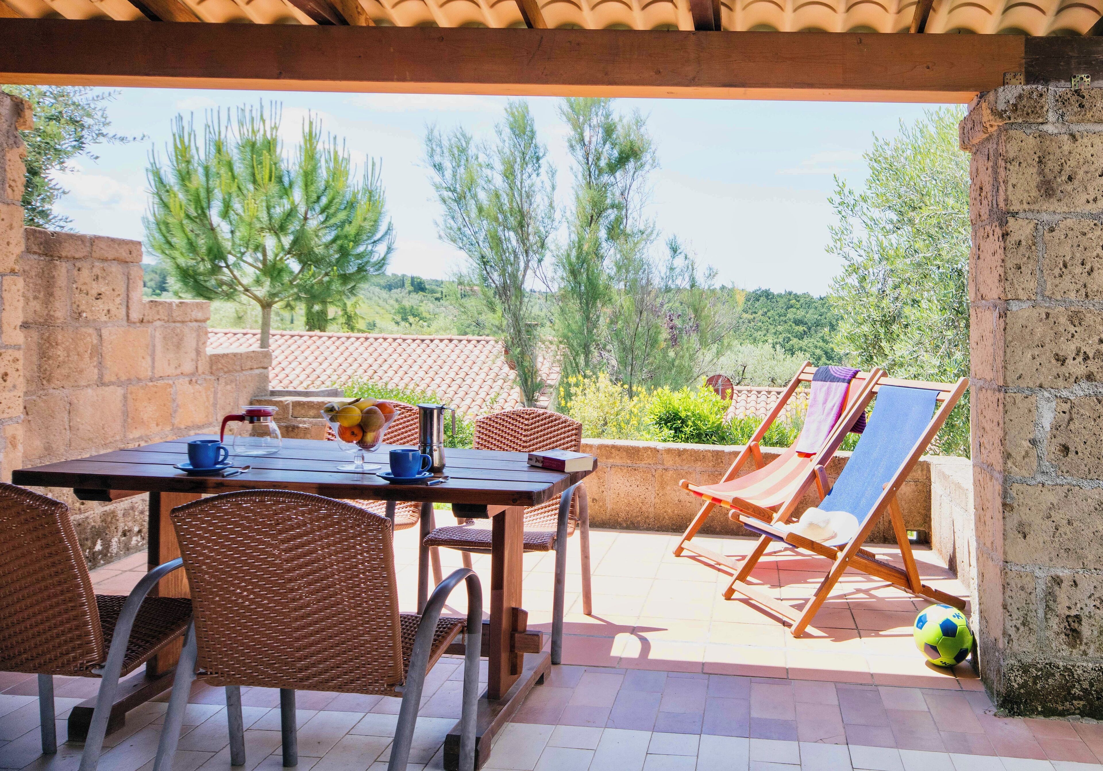 Un patio exterior con una mesa, sillas y una tumbona.