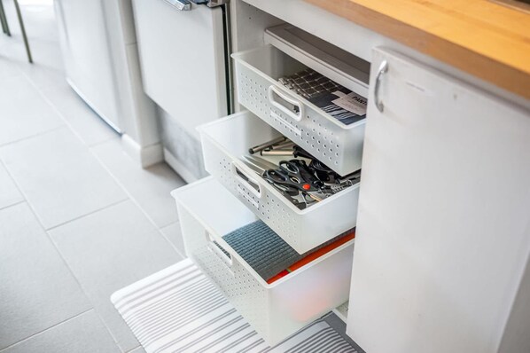 A kitchen with white cabinets, a wooden countertop, and a stainless steel range hood.