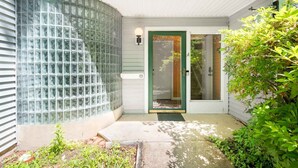 A house with a glass block wall, a green door, and a small garden area. - Charming Loft 5 Min Walk to Duke University (Durham)