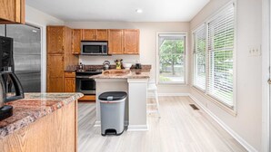Una cocina moderna con armarios de madera, microondas, estufa y encimeras de granito.