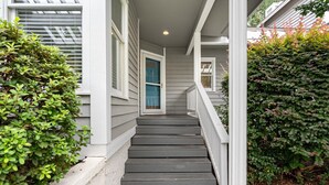 Una escalera conduce a la entrada de una casa, con barandillas blancas y una puerta azul.