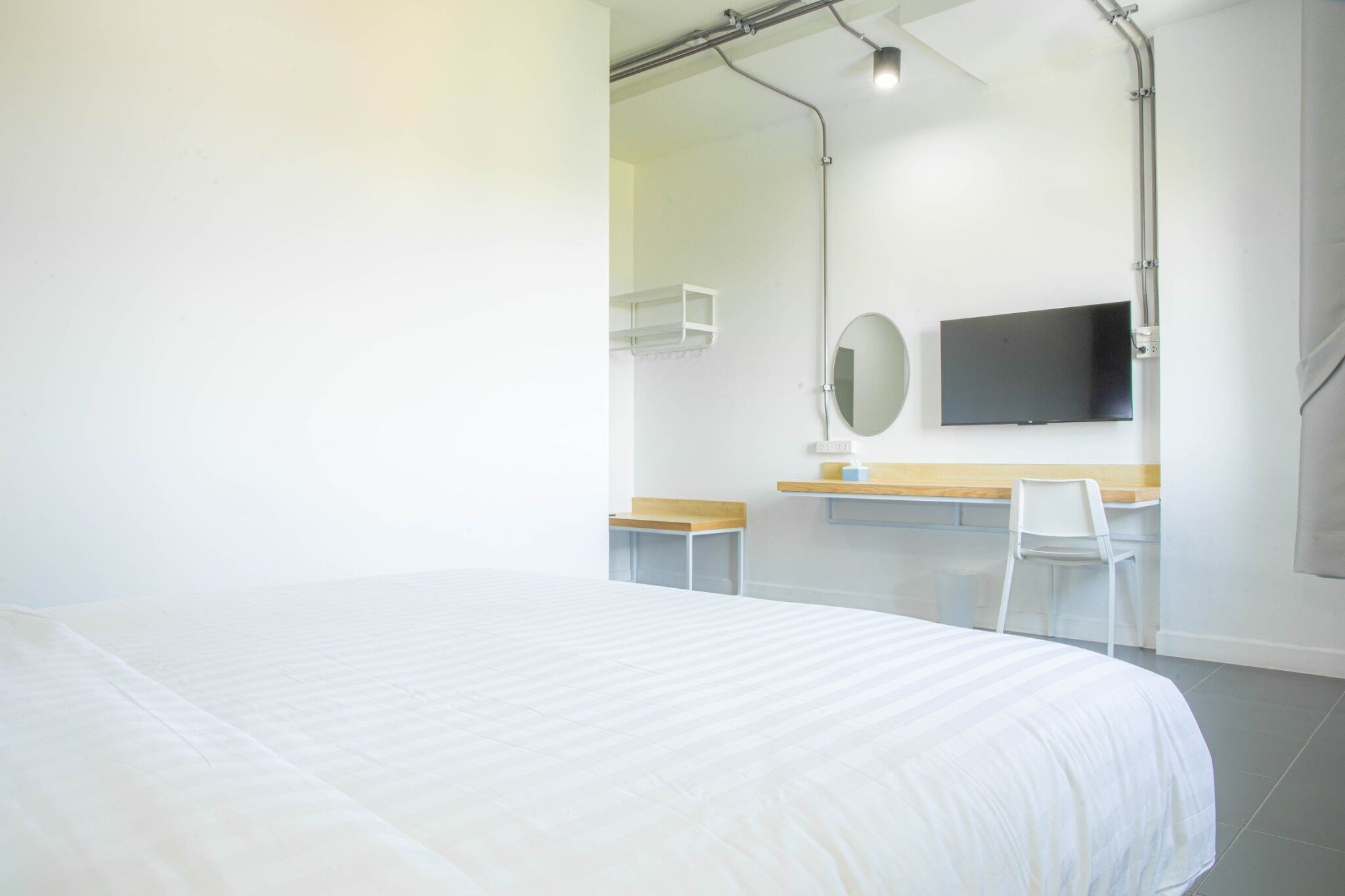 Habitación de hotel con cama, escritorio, silla, televisor y espejo.