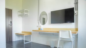 Ein modernes Zimmer mit einem Holztisch, einem weißen Stuhl, einem Spiegel und einem an der Wand befestigten Flachbildfernseher.