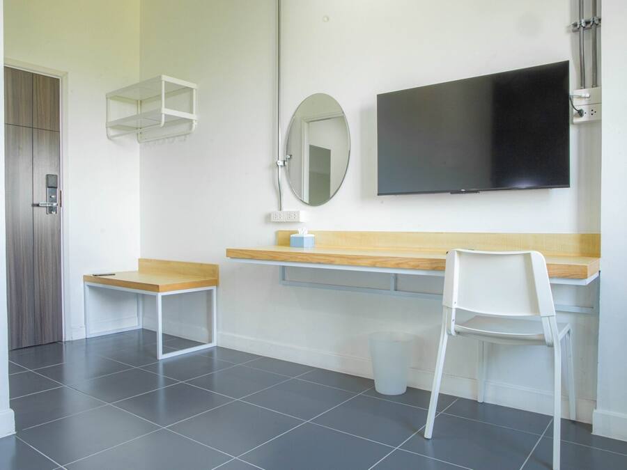 A modern room with a wooden desk, a white chair, a mirror, and a flat-screen TV mounted on the wall.