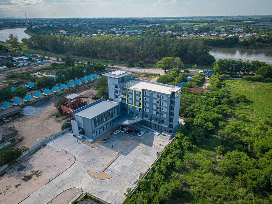 Un edificio de varios pisos con techo plano, rodeado de vegetación y un río.