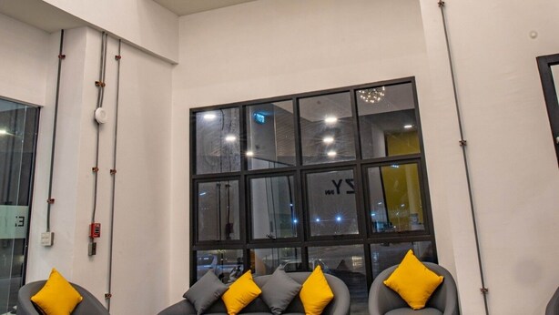 Ein modernes Interieur mit grauen Sofas und gelben Kissen, großen Fenstern und dekorativen, kugelförmigen Lampen.