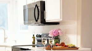 A kitchen with a white island, a stainless steel microwave, and a vase with flowers. - HotTub-Fire Pit-Outdoor Dining-EV Charger (East Wenatchee)