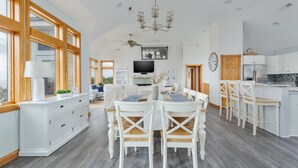 Eine geräumige Küche mit weißen Schränken, eine Essecke mit einem Holztisch und Stühlen sowie ein großes Fenster, das für natürliches Licht sorgt.