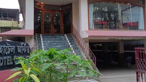A hotel entrance with a staircase leading to the main building, surrounded by greenery and a metal fence. - Hotel Orchid (Guwahati)