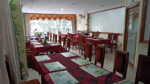 A restaurant with multiple tables and chairs, some with menus. - Hotel Orchid (Guwahati)