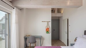 A bedroom with a bed, a desk, and a chair. There is a window with curtains, a door, and a wall-mounted towel rack with a towel. - Luxury Villa Dana Indoor Pool and Sauna (Matulji)