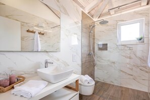 Ein modernes Badezimmer mit großem Spiegel, einem Aufsatzwaschbecken, einer Dusche und einer Toilette.