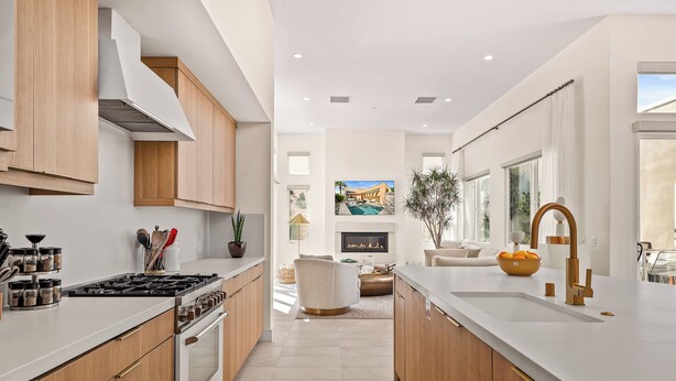 Une cuisine moderne avec des meubles en bois, une cuisinière et un coin repas offrant une vue sur une piscine.