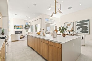A modern kitchen with a central island, wooden cabinets, and a large window.