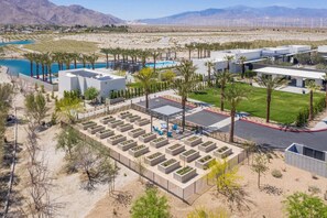 A modern resort with a pool, palm trees, and a desert landscape.