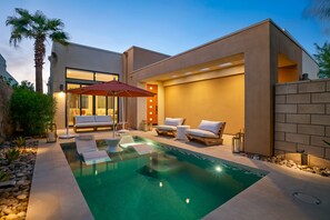 A modern outdoor pool area with lounge chairs and a covered seating area.